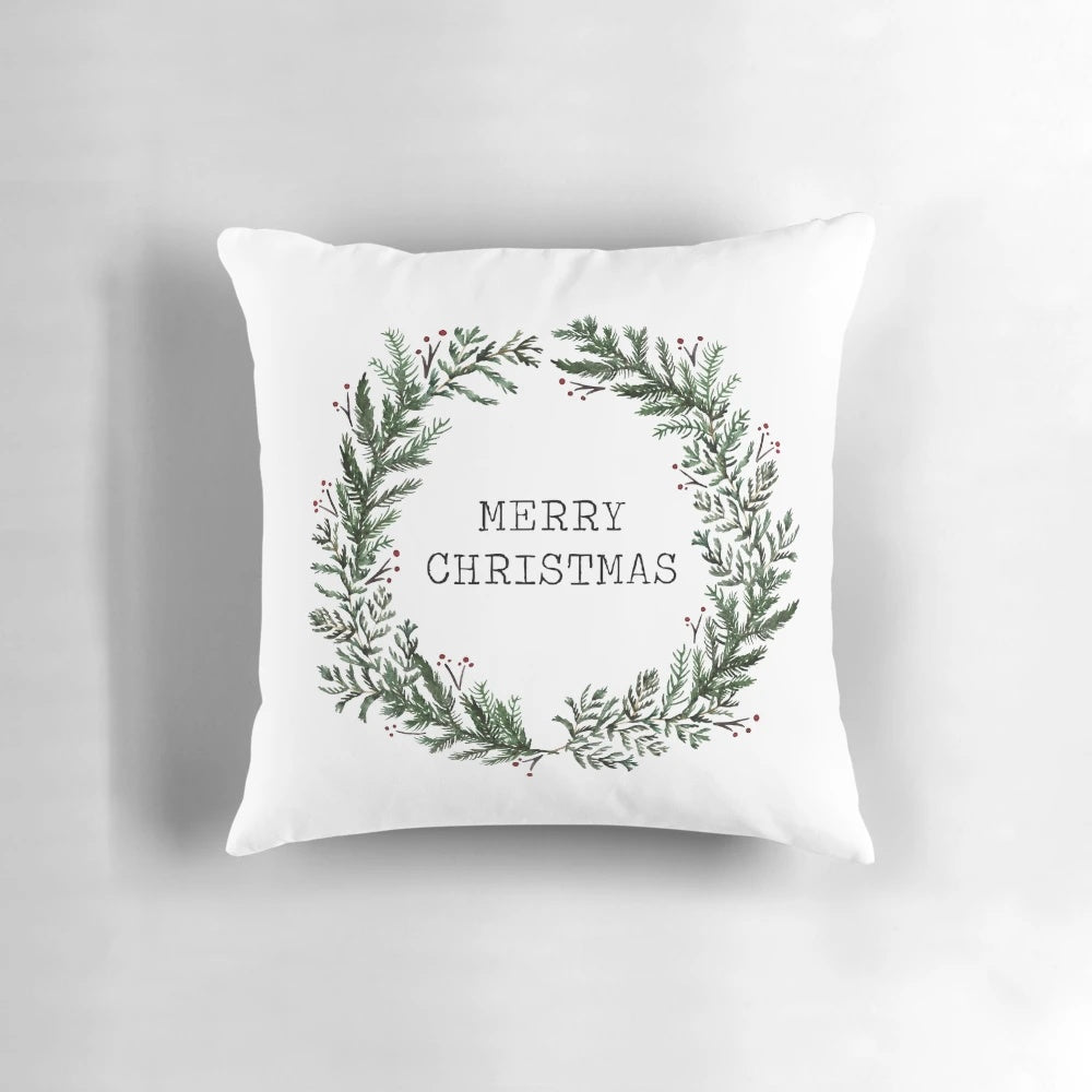 A simple, merry Christmas-themed throw pillow with a watercolor wreath design on a green background.