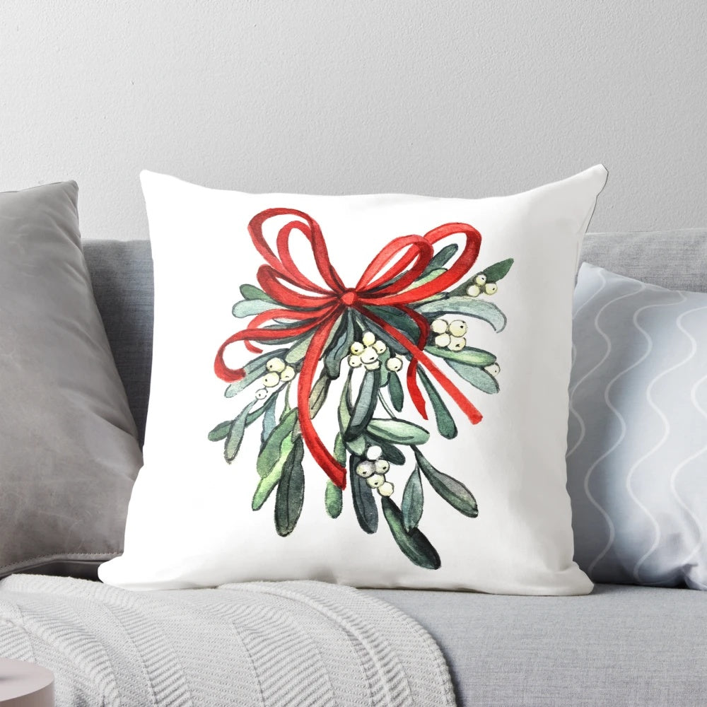A decorative pillow featuring a branch of green mistletoe with white berries, a classic symbol of the holiday season.