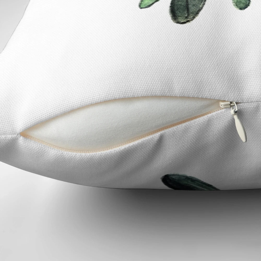 A decorative pillow featuring a branch of green mistletoe with white berries, a classic symbol of the holiday season.