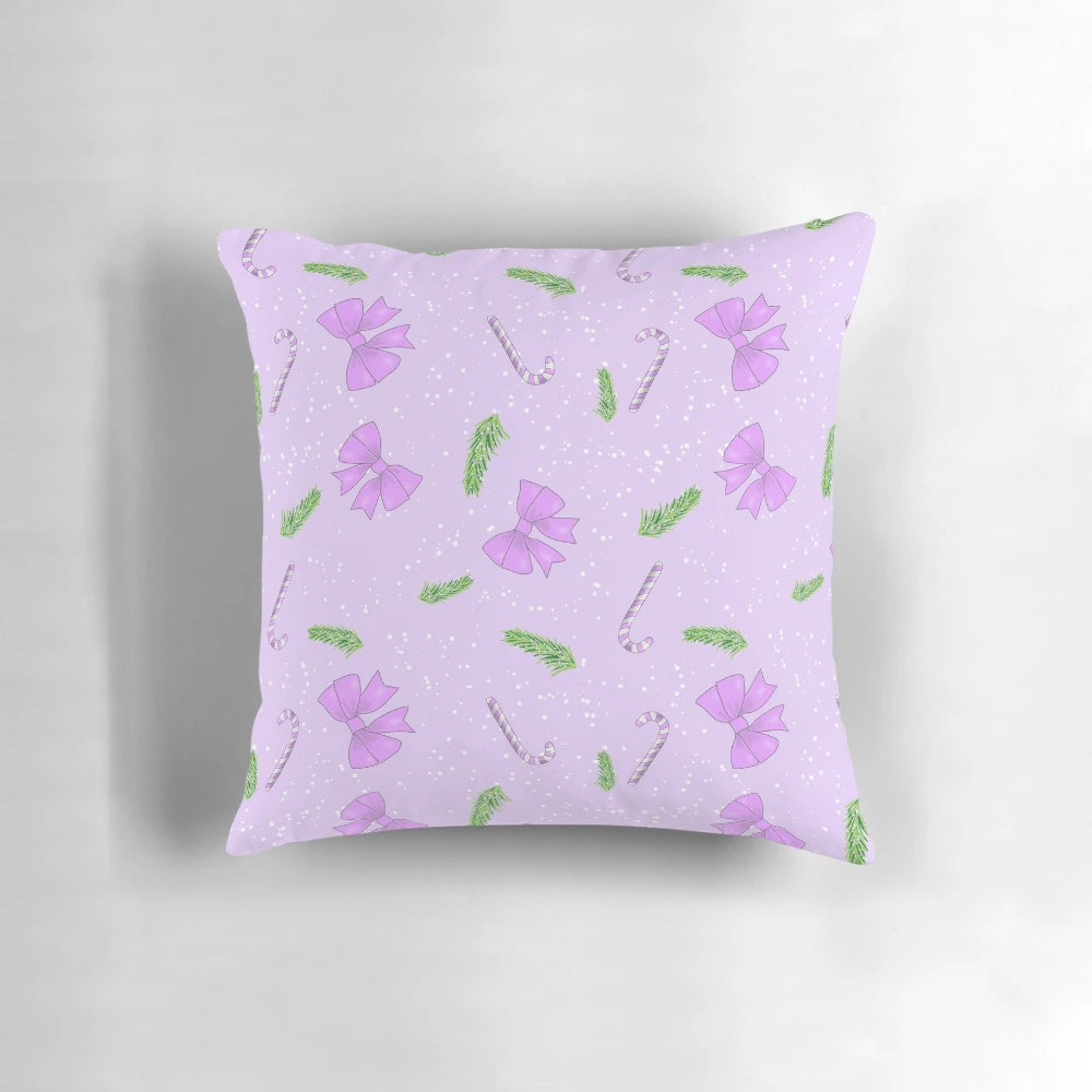 A soft, pink pillow with a festive Christmas pattern of bows, spruce, candy canes, and snow.