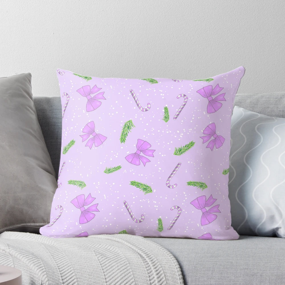 A soft, pink pillow with a festive Christmas pattern of bows, spruce, candy canes, and snow.