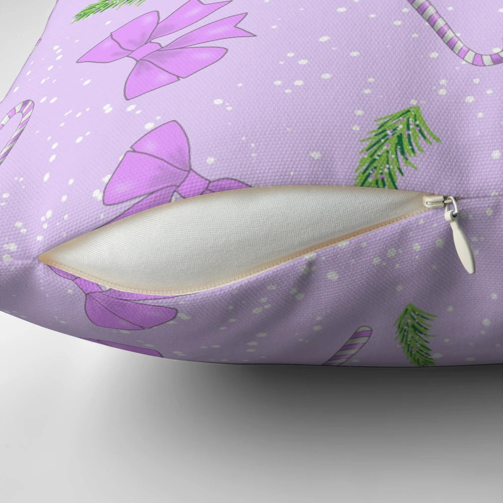 A soft, pink pillow with a festive Christmas pattern of bows, spruce, candy canes, and snow.