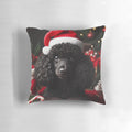 A black miniature poodle wearing a Santa hat on a Christmas-themed decorative pillow.