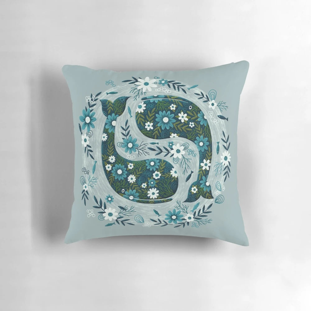 A decorative throw pillow featuring a floral and whale design in shades of blue and green.