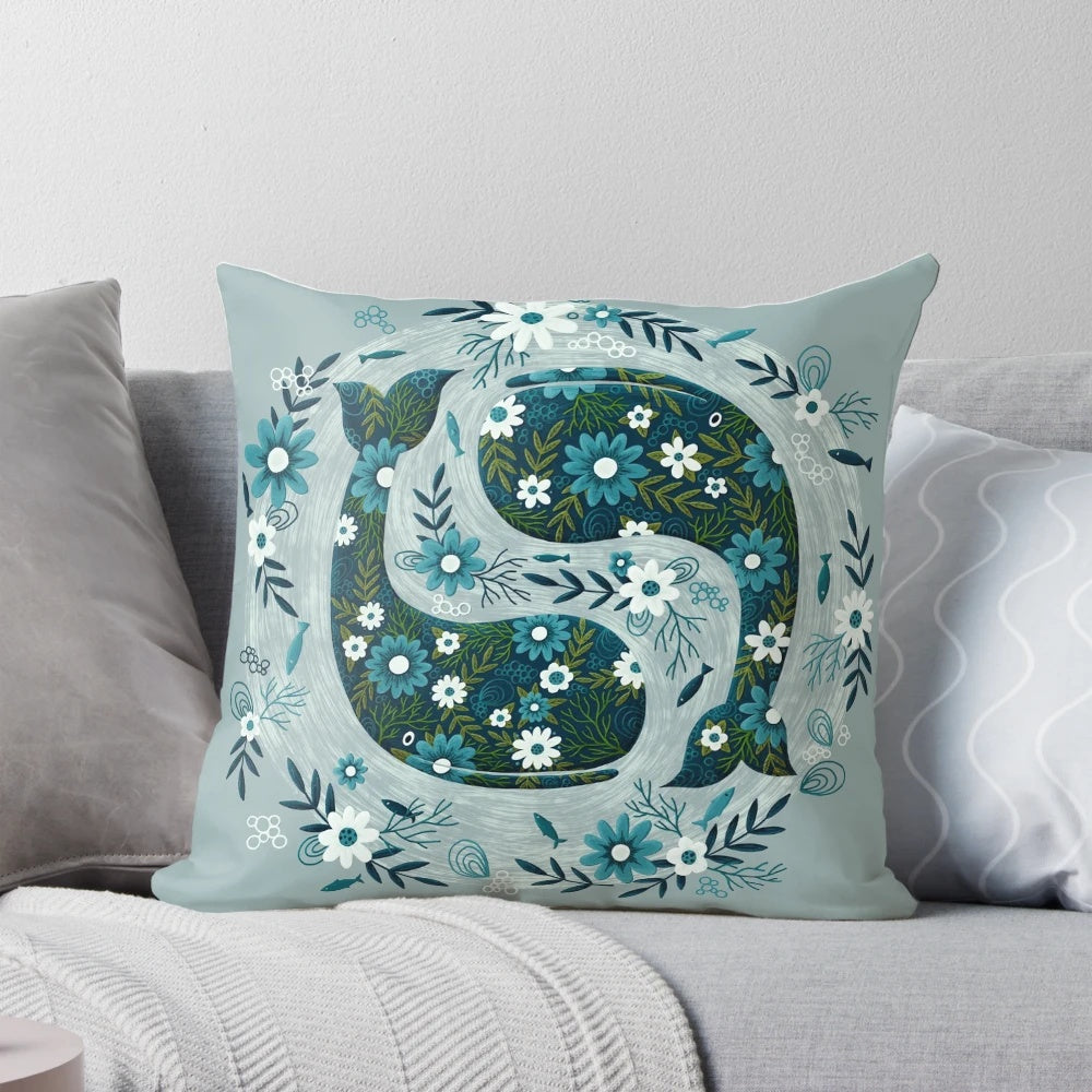 A decorative throw pillow featuring a floral and whale design in shades of blue and green.