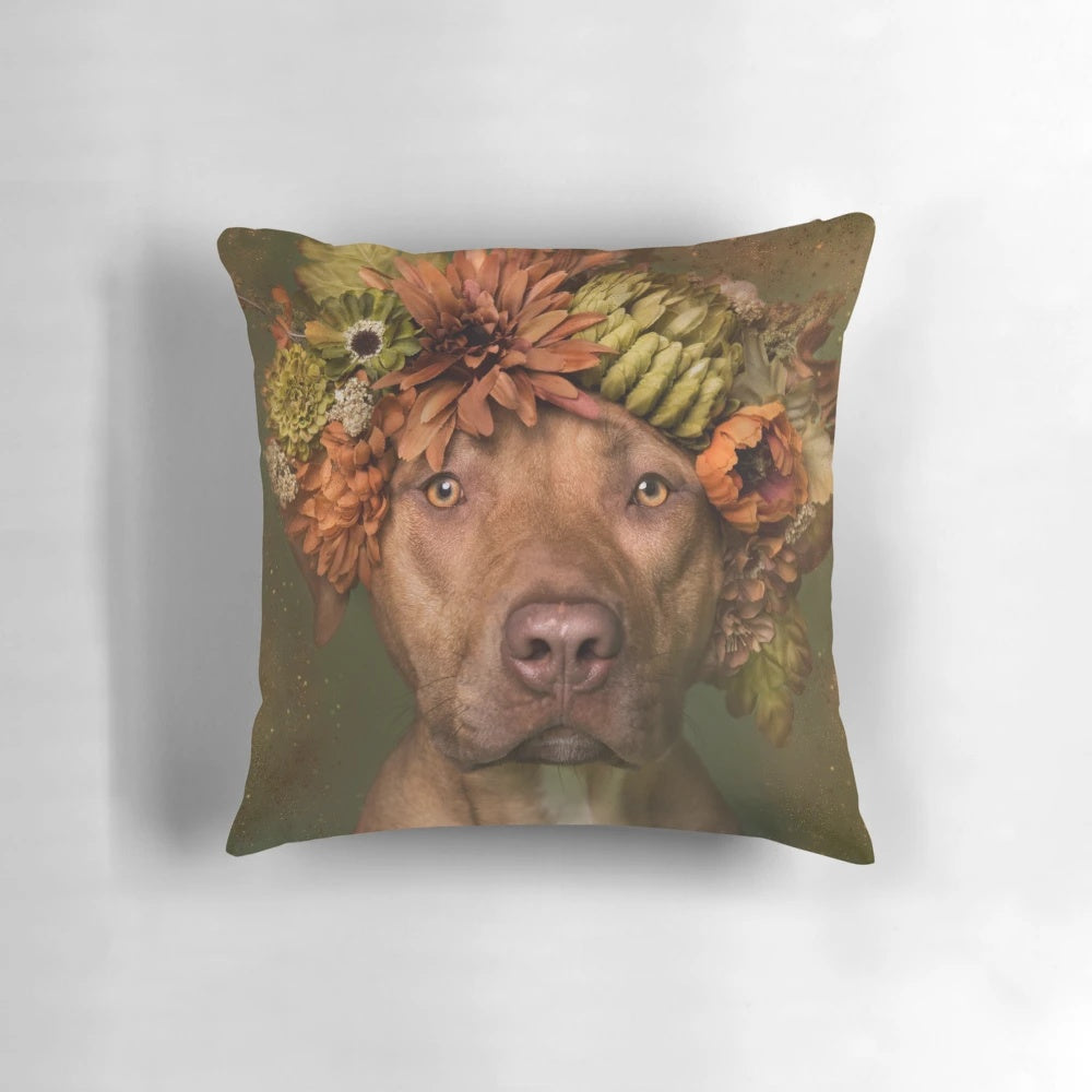 A plush pillow featuring a pit bull wearing a colorful flower crown against a botanical background.