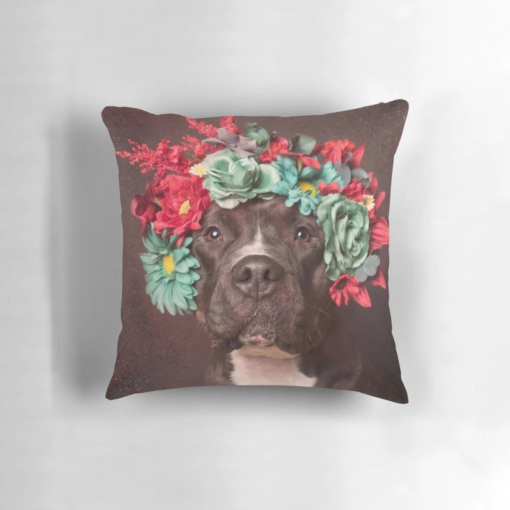 A plush, decorative pillow featuring a pitbull wearing a whimsical flower crown design.