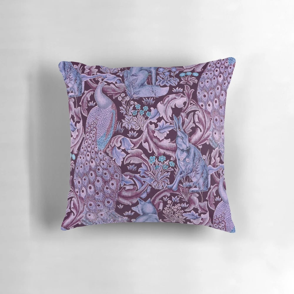 Decorative throw pillow featuring a whimsical forest animal and peacock floral pattern in shades of blue and purple.