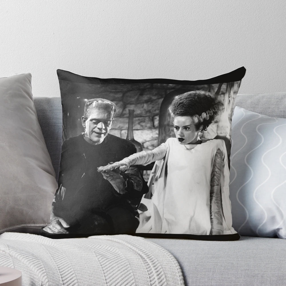 Frankenstein and his bride holding hands on a decorative throw pillow