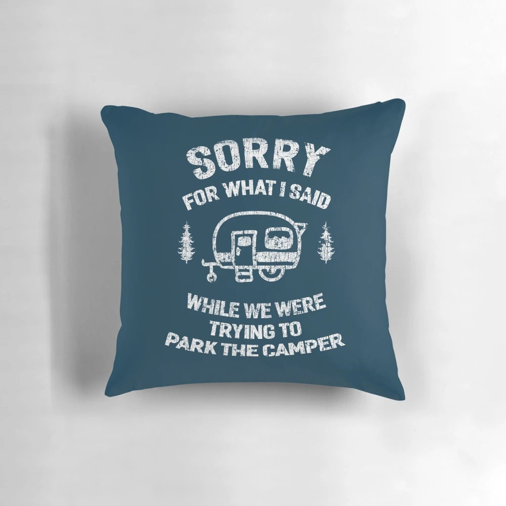 A white and blue pillow with the text "Sorry for what I said while we tried to park the camper" printed on it.