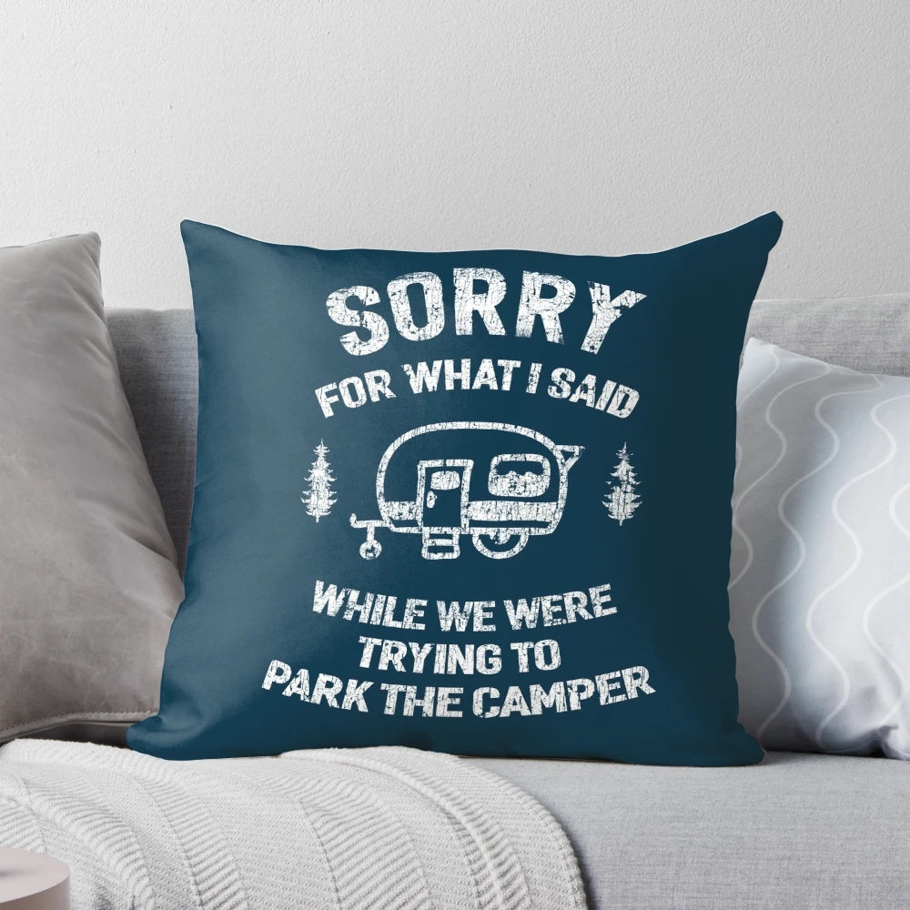 A white and blue pillow with the text "Sorry for what I said while we tried to park the camper" printed on it.