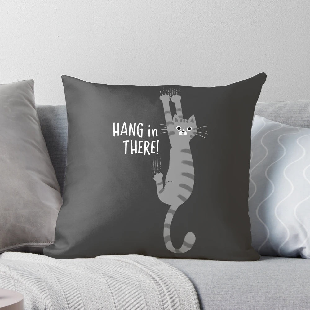 Gray striped tabby cat hanging on a pillow with the text "Hang in There!