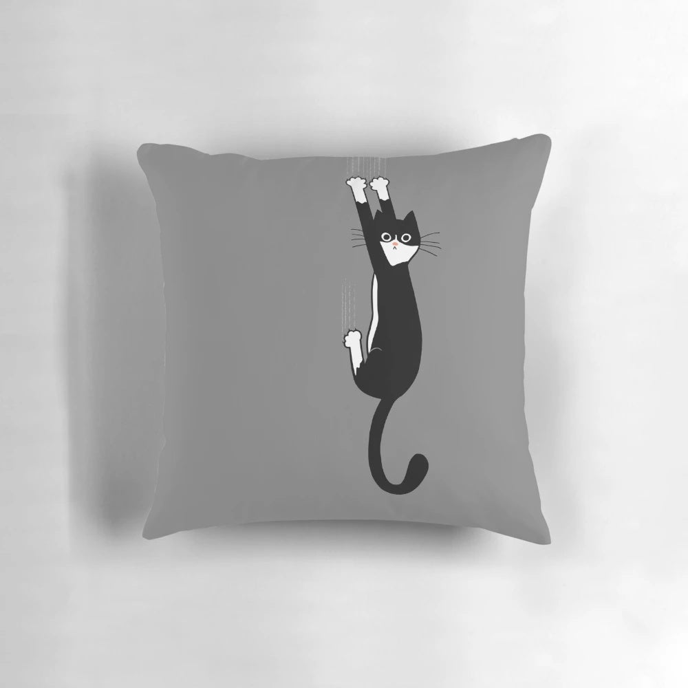 A black and white tuxedo cat hanging on to a pillow with a cartoon illustration design