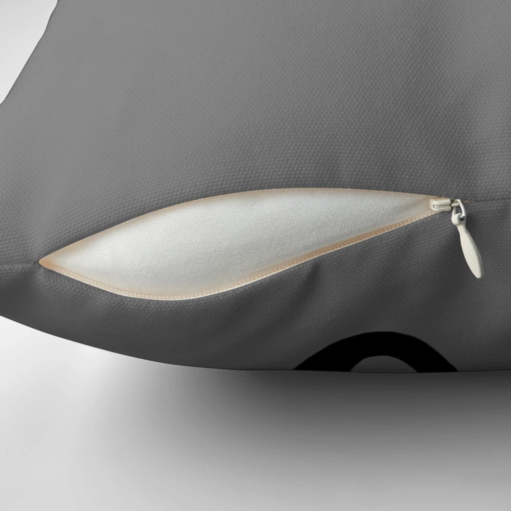 A black and white tuxedo cat hanging on to a pillow with a cartoon illustration design