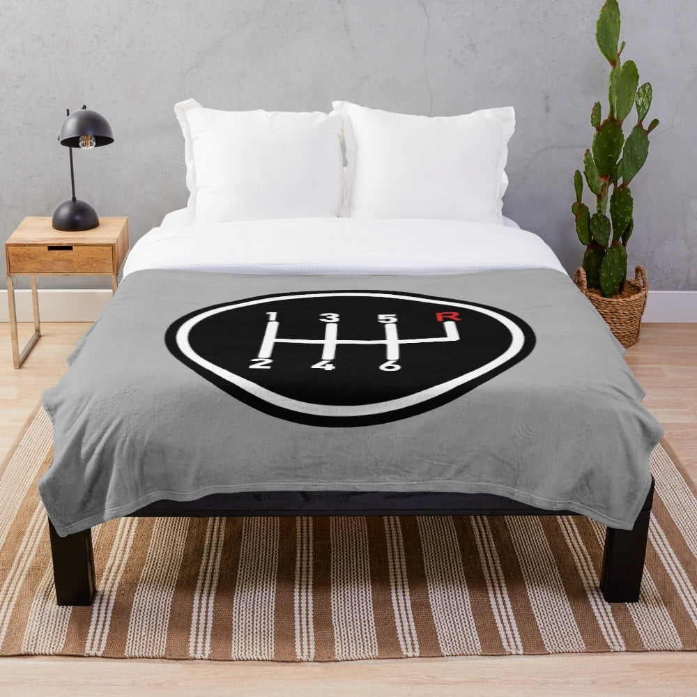 Plush blanket featuring a red manual transmission logo