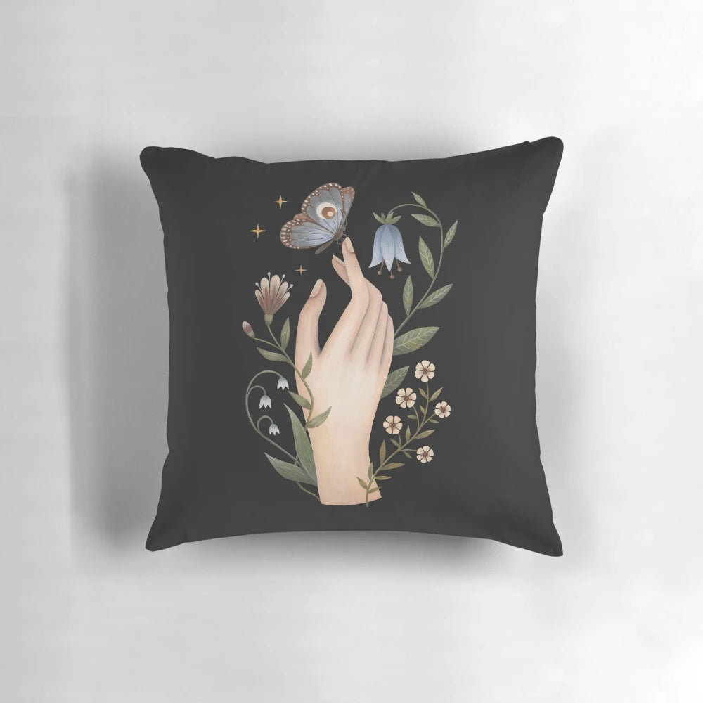 A close-up of a hand-painted nature and floral design with a butterfly on a black pillow.