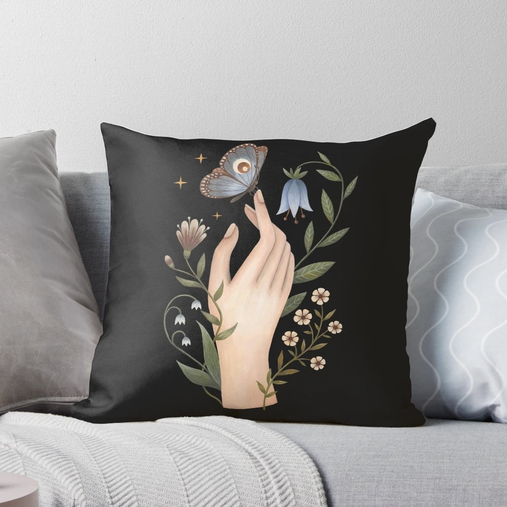 A close-up of a hand-painted nature and floral design with a butterfly on a black pillow.