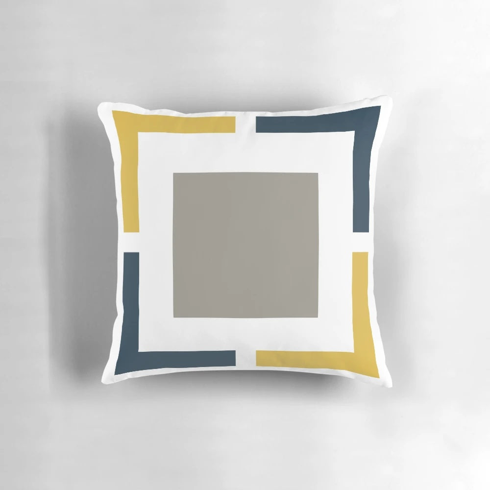 A square pillow with a geometric pattern in light mustard yellow, navy blue, white, and grey colors.