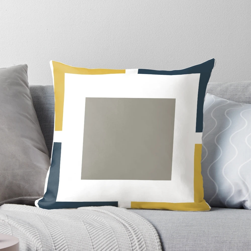 A square pillow with a geometric pattern in light mustard yellow, navy blue, white, and grey colors.