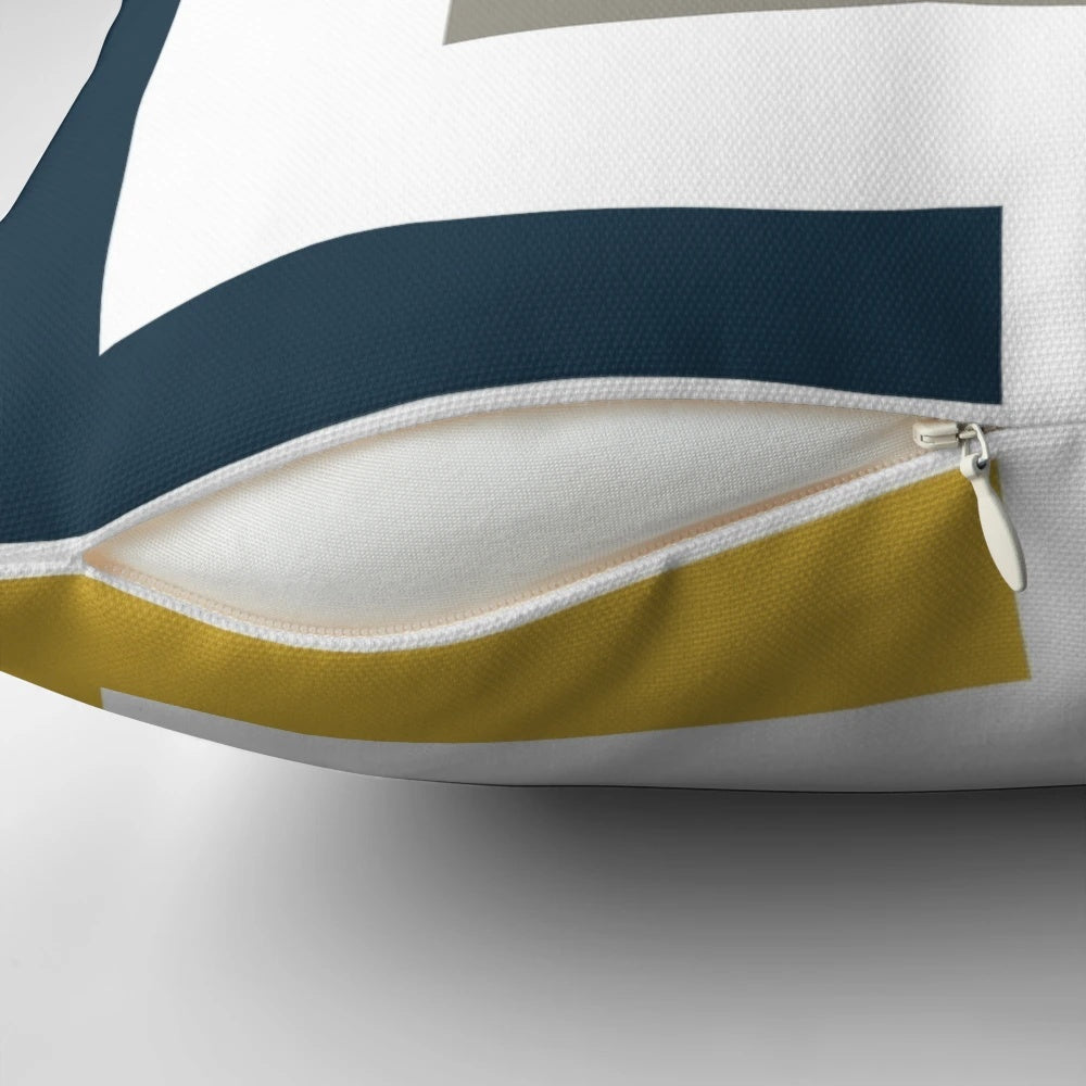 A square pillow with a geometric pattern in light mustard yellow, navy blue, white, and grey colors.