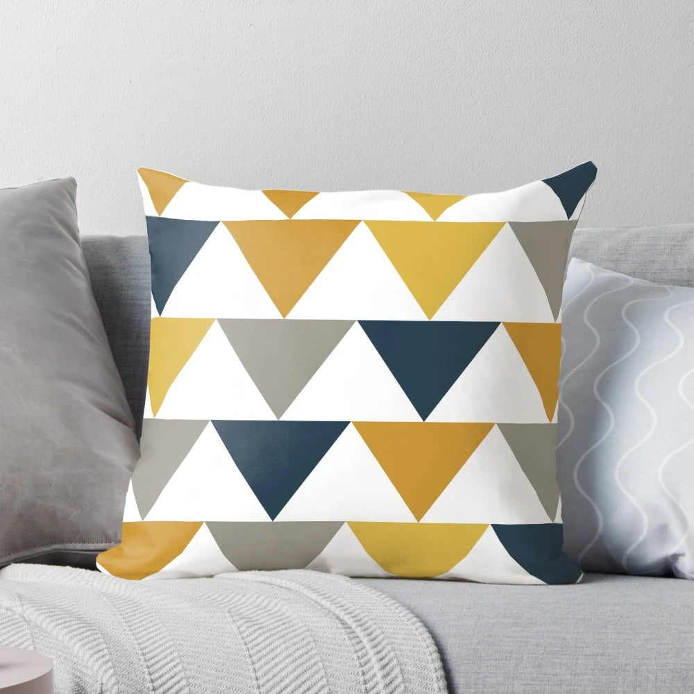 A geometric pattern pillow in shades of mustard yellow, gray, and blue