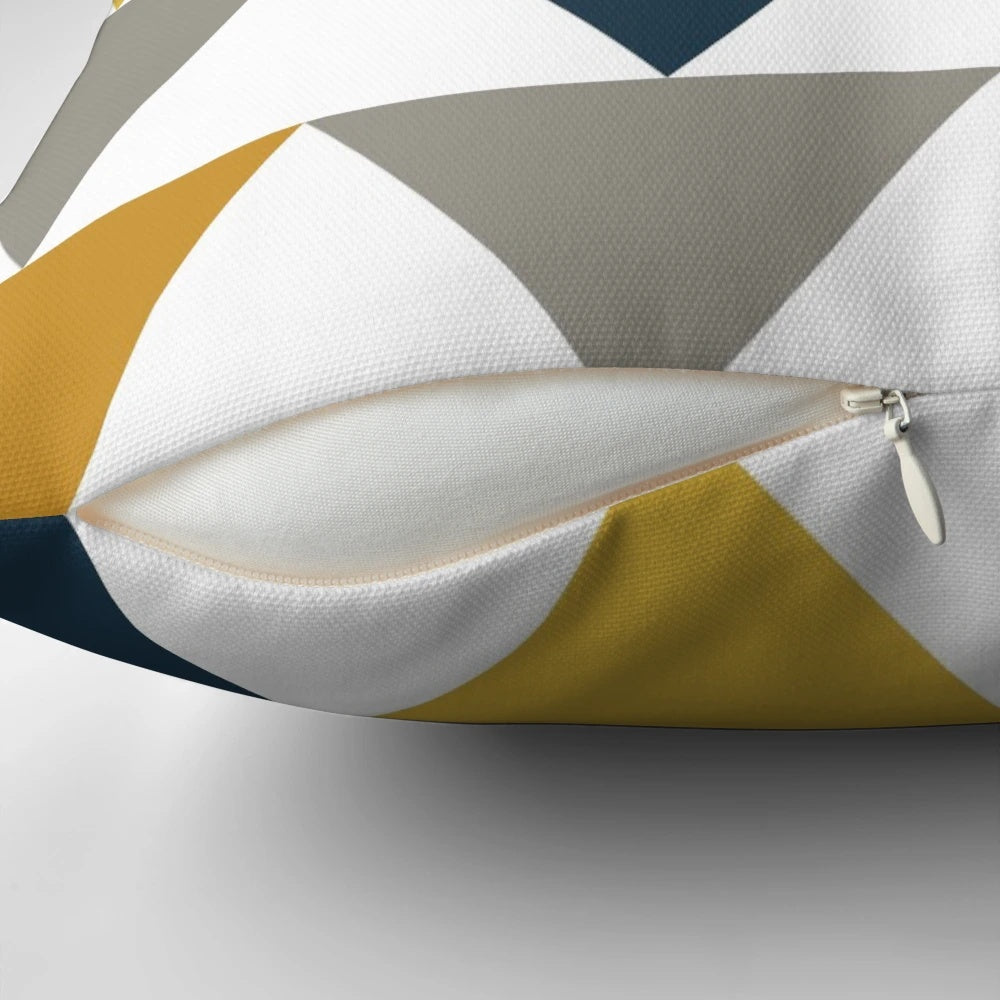 A geometric pattern pillow in shades of mustard yellow, gray, and blue