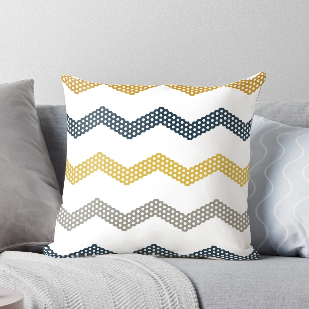 A decorative throw pillow featuring a minimalist honeycomb chevron pattern in shades of mustard yellow, dark blue, grey, and white.