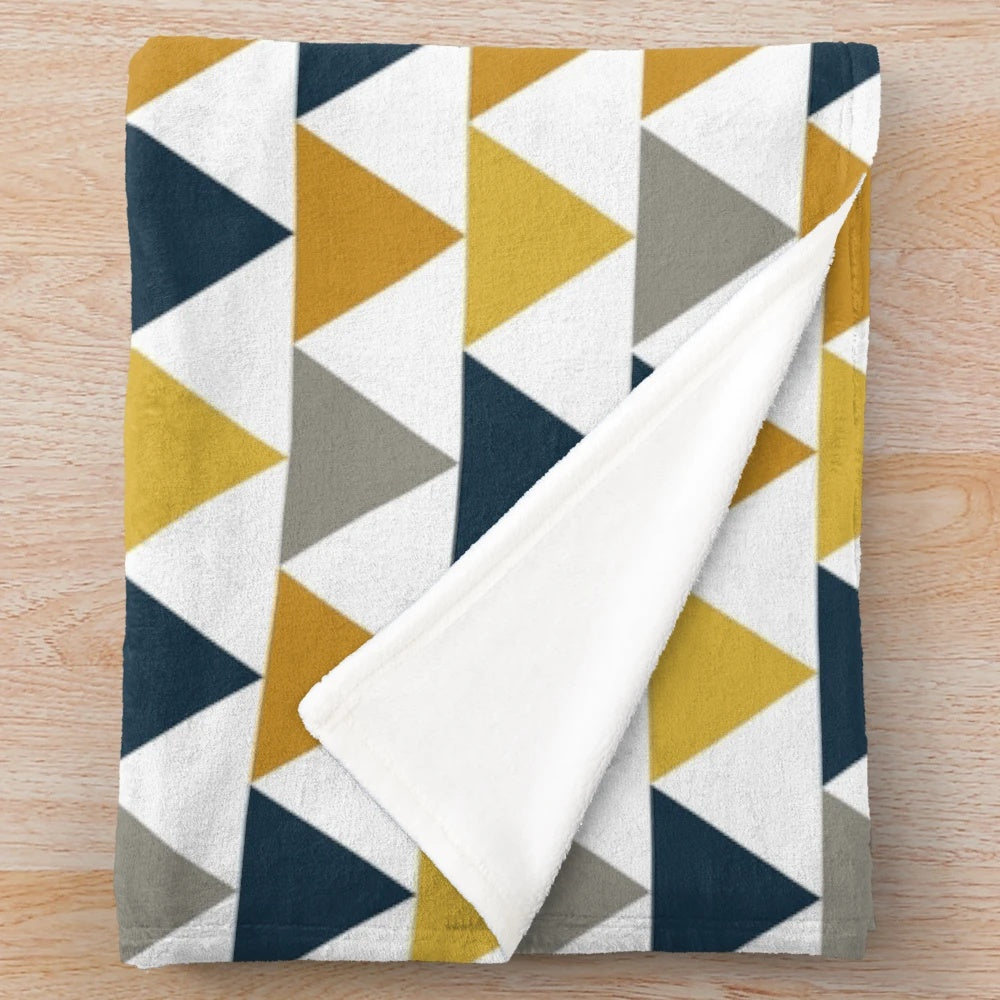 Geometric pattern plush blanket in mustard yellow, dark blue, and gray colors
