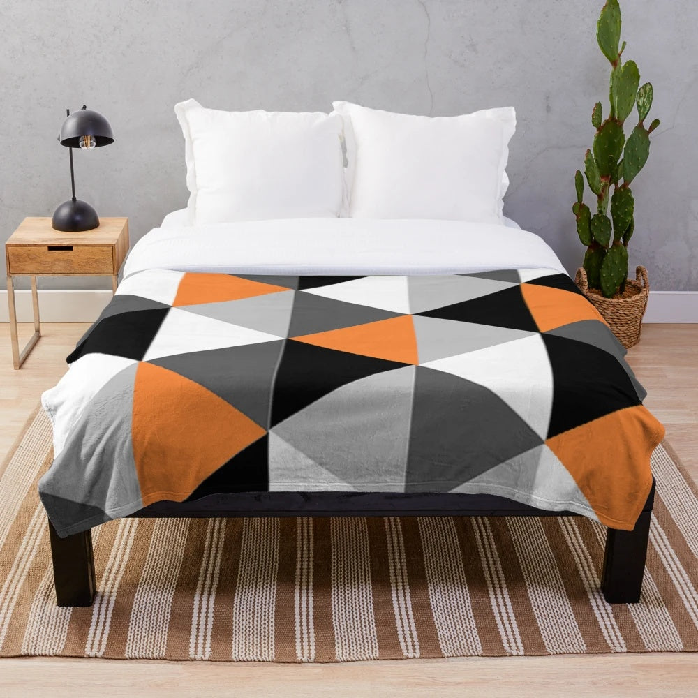 Geometric pattern plush blanket in orange, black, white, and grey colors
