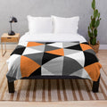 Geometric pattern plush blanket in orange, black, white, and grey colors