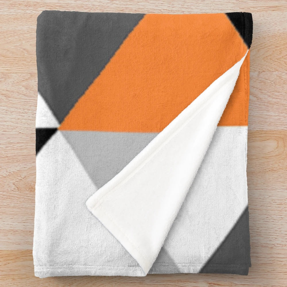 Geometric pattern plush blanket in orange, black, white, and grey colors