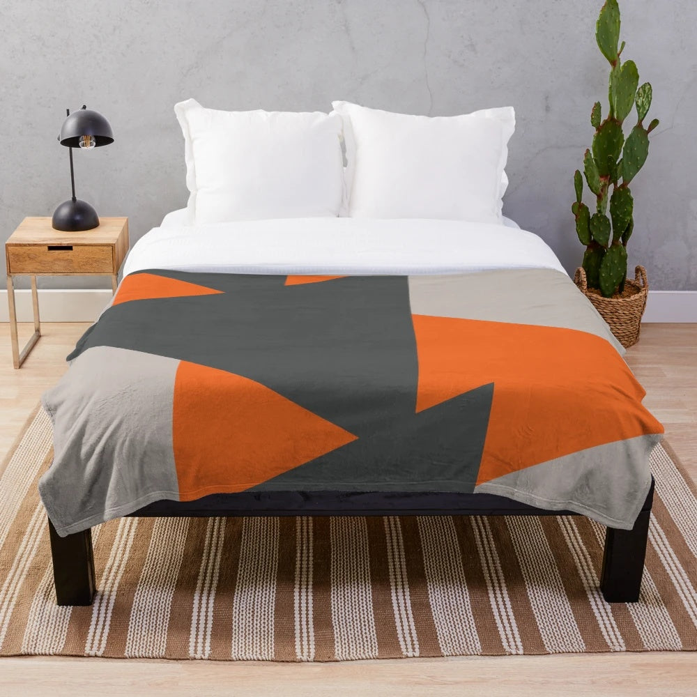 Cozy plush blanket featuring a geometric triangle pattern in orange and grey