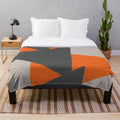 Cozy plush blanket featuring a geometric triangle pattern in orange and grey