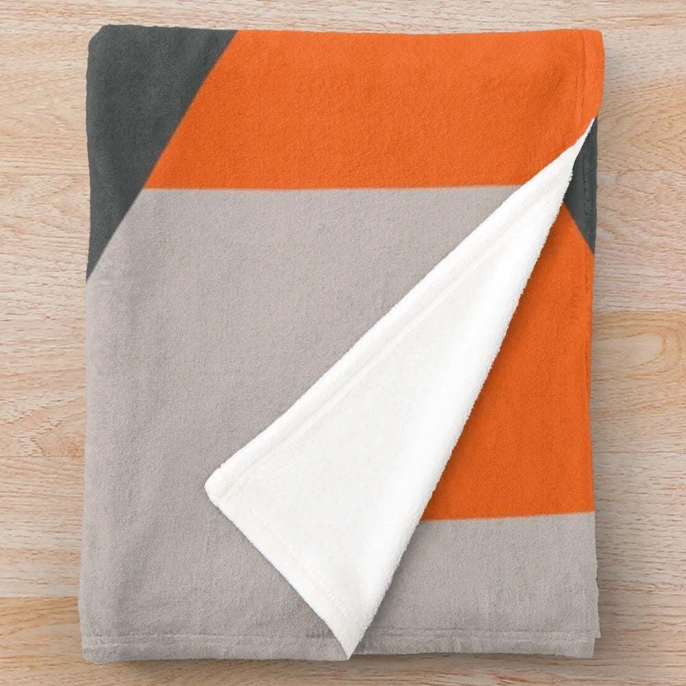 Cozy plush blanket featuring a geometric triangle pattern in orange and grey