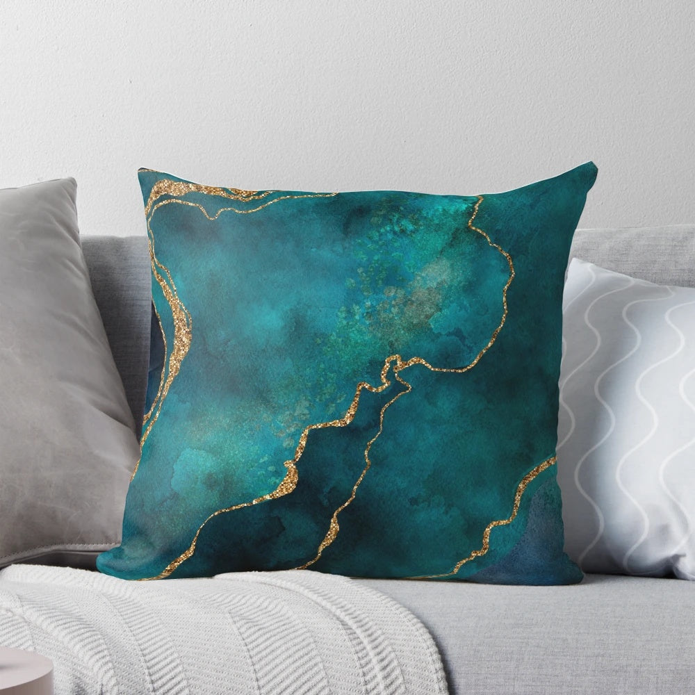 A decorative pillow featuring a golden and teal watercolor design with gemstones and minerals.