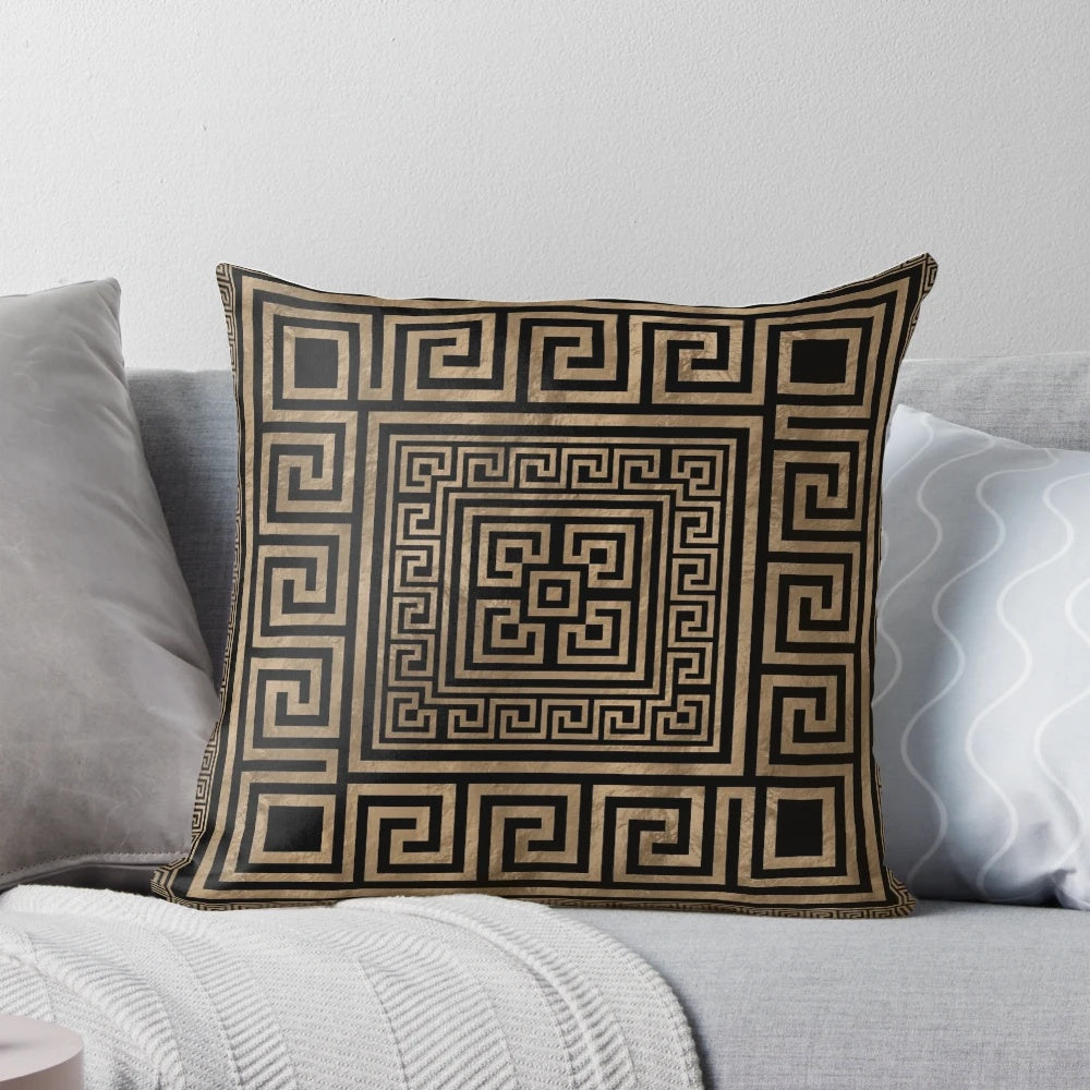 Decorative throw pillow featuring a Greek key ornament and meander pattern in gold on a black background.