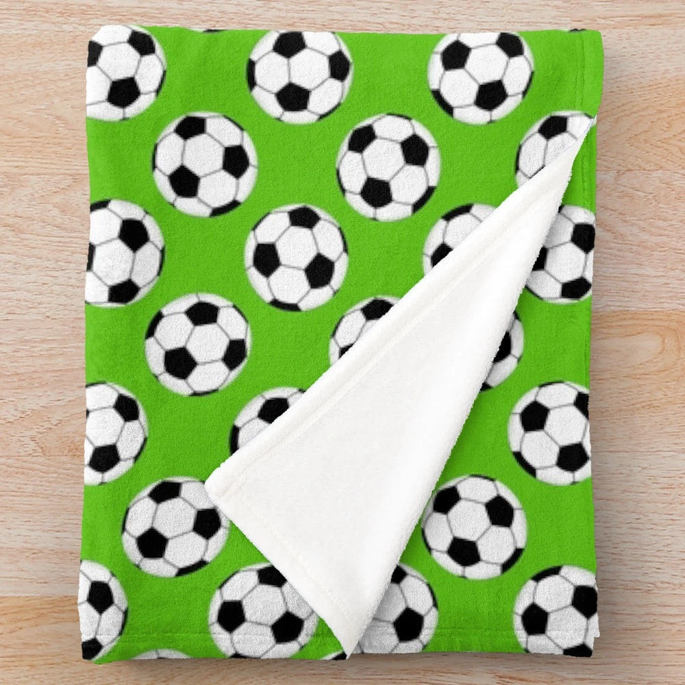 Green plush blanket with a black and white soccer ball pattern