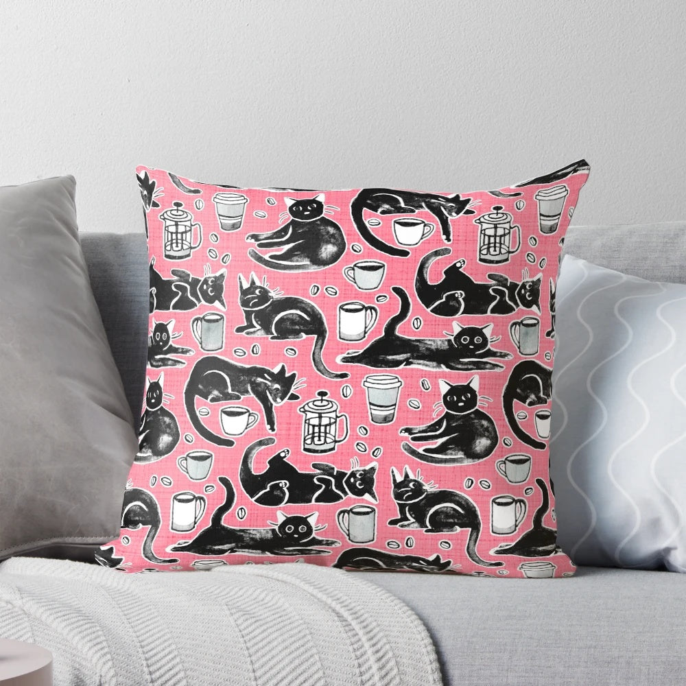 A decorative pillow featuring a hand-painted pattern of black cats on a strawberry pink background.