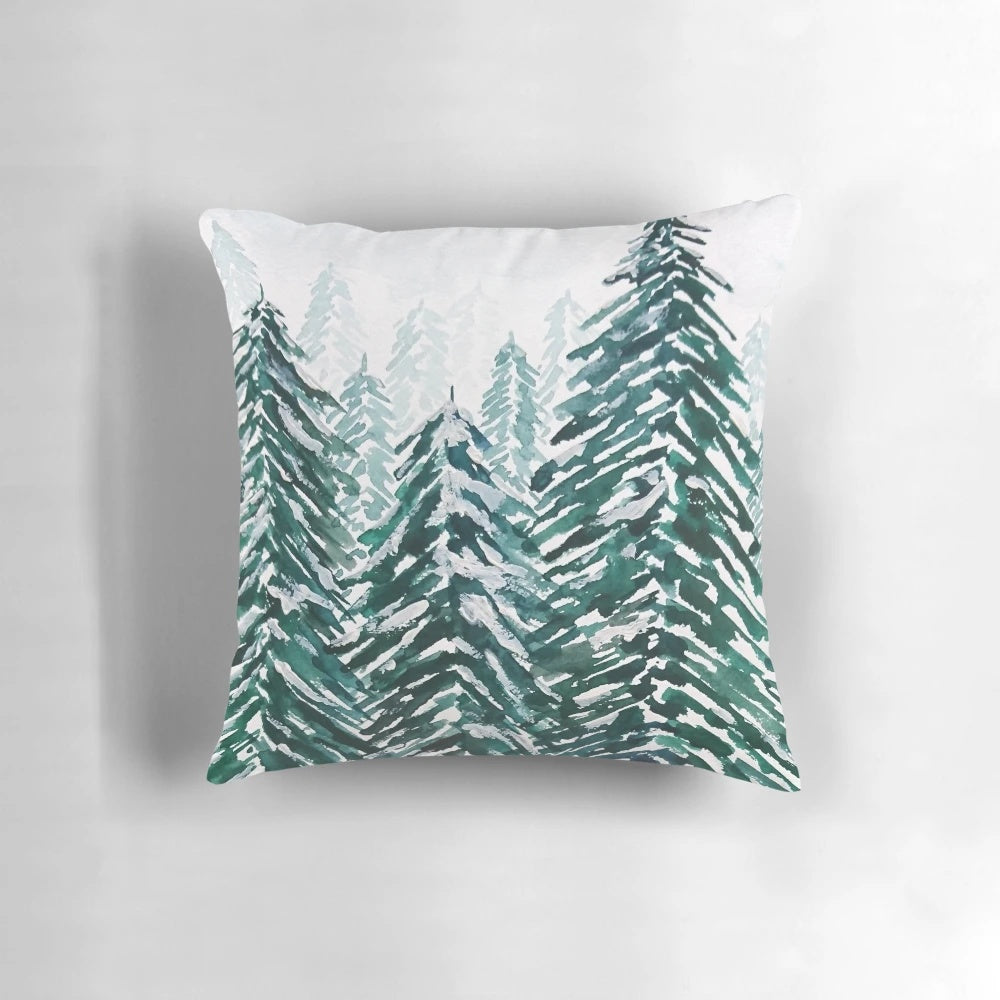 Handpainted green and white pillow with a snowy pine forest landscape design