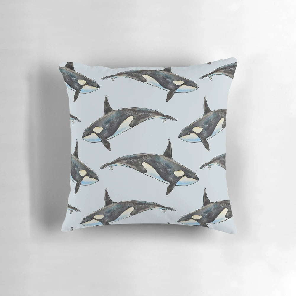 A beautifully hand-painted watercolor illustration of an orca whale on a blue background, featured on a decorative pillow.