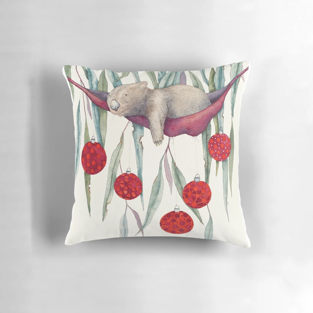 A colorful, water color style Christmas pillow featuring a wombat hanging in a gum tree with festive bobbles.