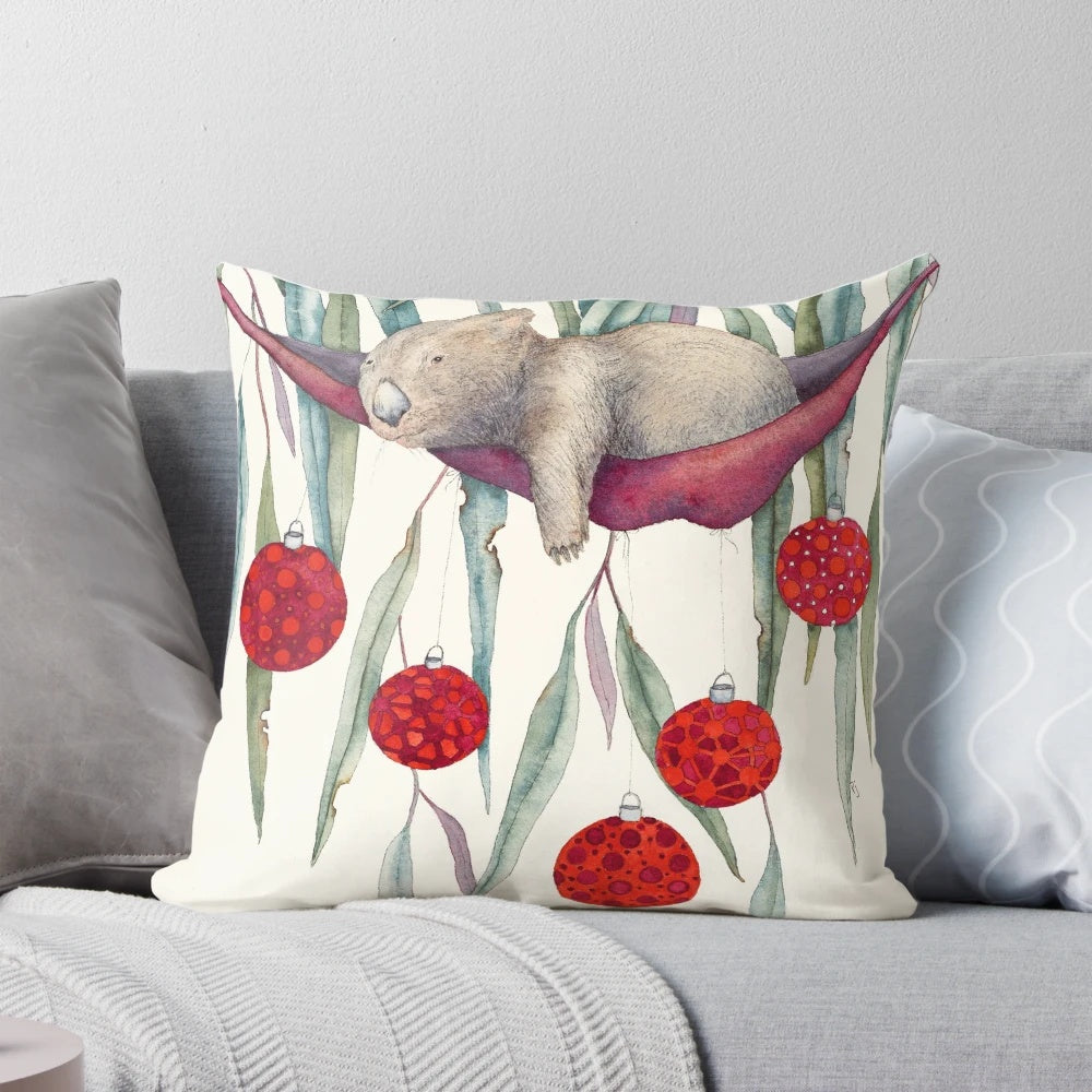 A colorful, water color style Christmas pillow featuring a wombat hanging in a gum tree with festive bobbles.