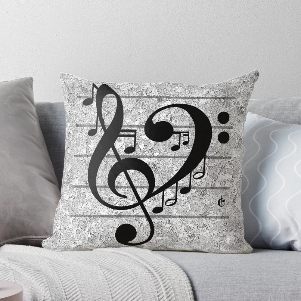 A grey pillow with a heart-shaped design featuring musical notes, treble and bass clefs, and other music symbols.