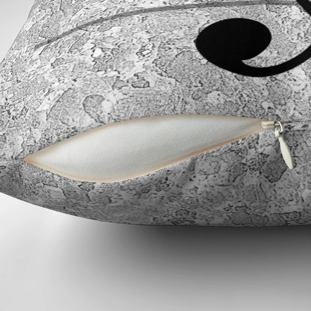 A grey pillow with a heart-shaped design featuring musical notes, treble and bass clefs, and other music symbols.