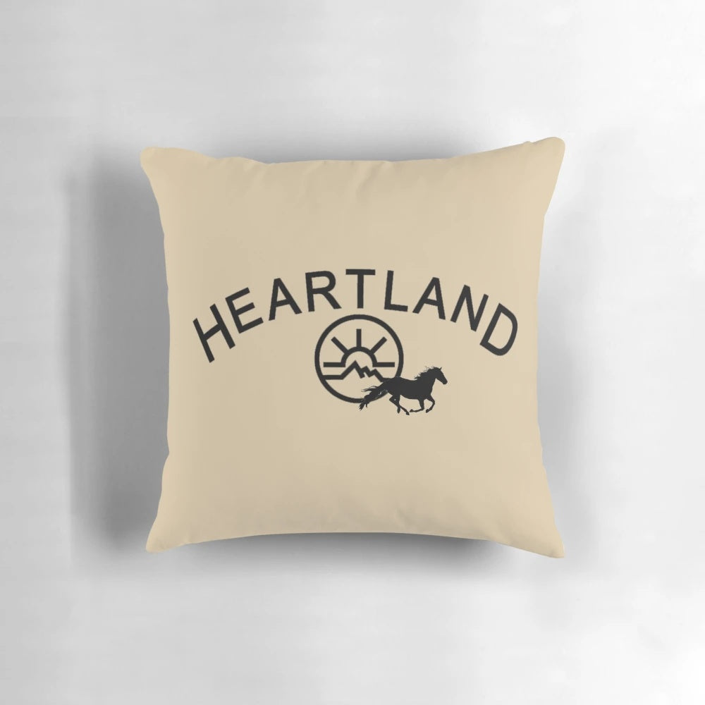 A black pillow with the Heartland TV show logo, featuring horses and the Montana landscape.