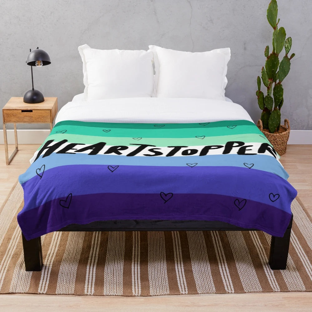 Heartstopper inspired plush blanket featuring the gay pride flag colors and logo