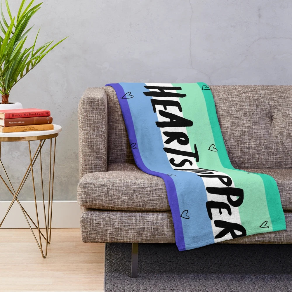 Heartstopper inspired plush blanket featuring the gay pride flag colors and logo