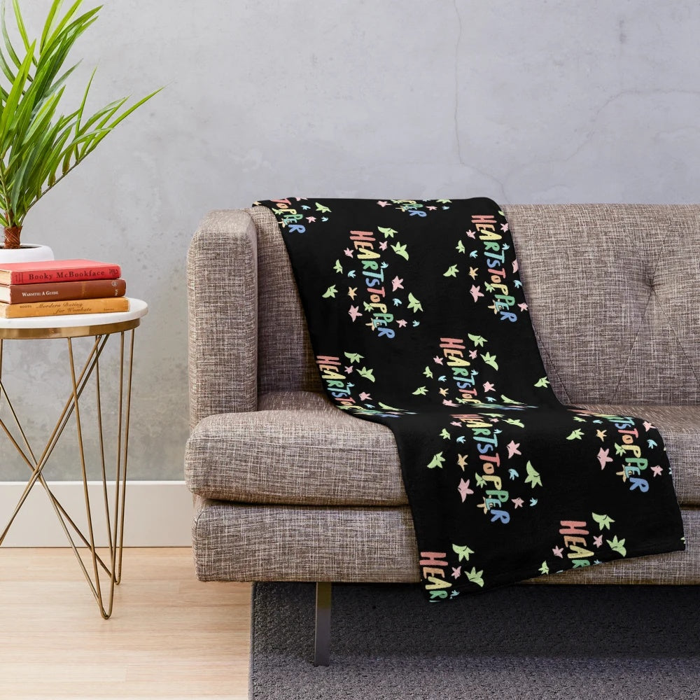 Heartstopper-inspired plush blanket with a black background and a design of leaves