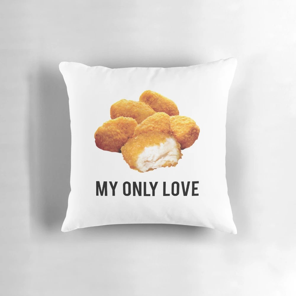 A white, square pillow with the text "chicken nuggets my only love" printed on it.