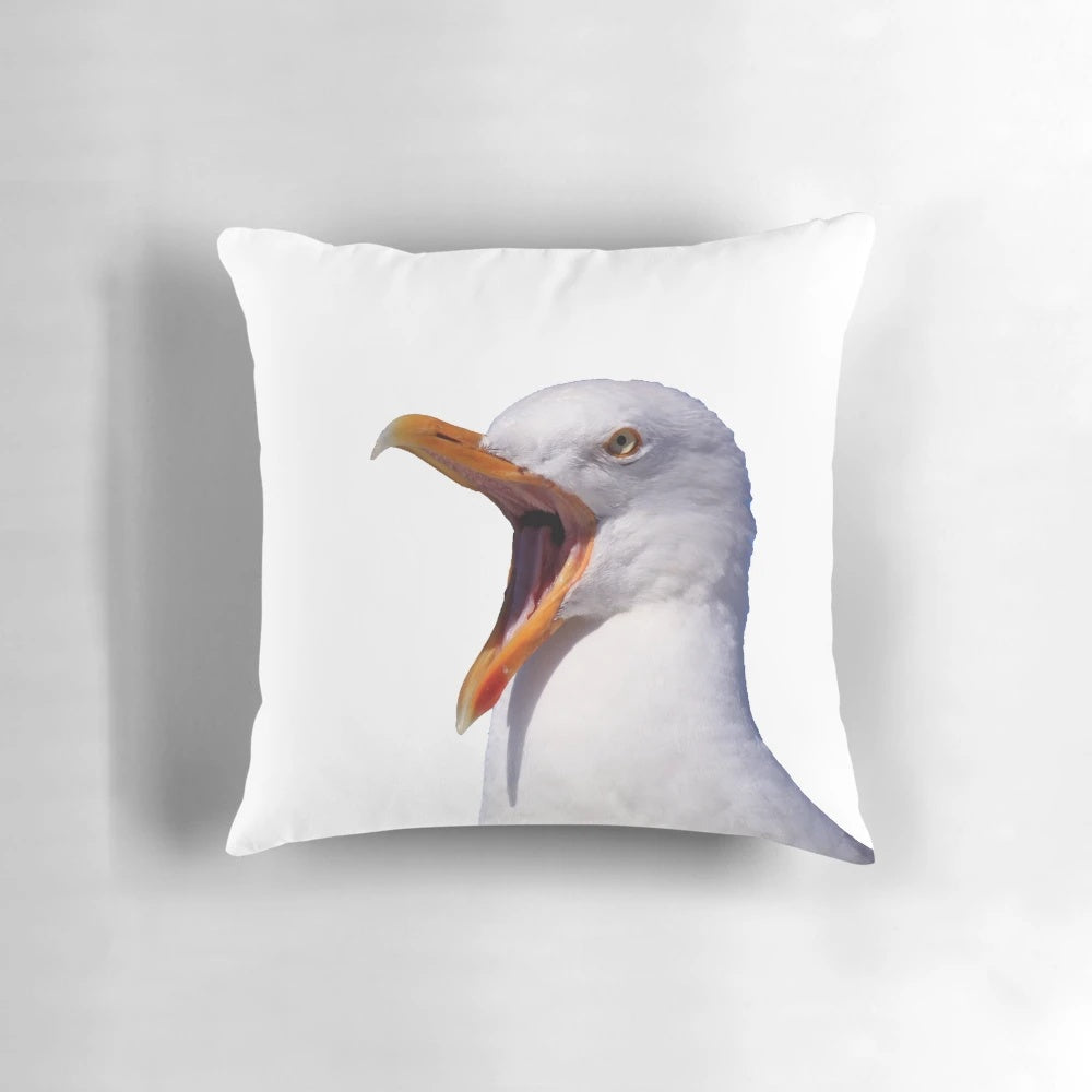 A white and yellow seagull with an open beak screaming on a pillow.